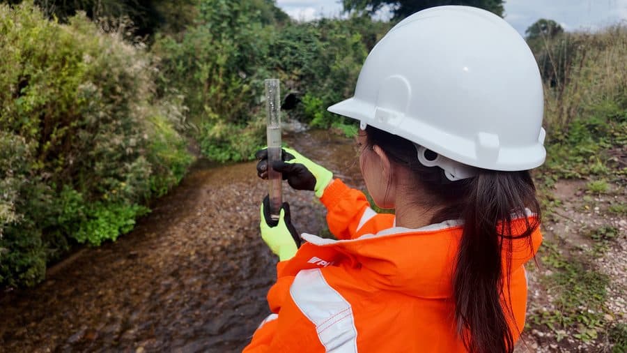 Environmental officer examining a turbidity reading beside a watercourse
