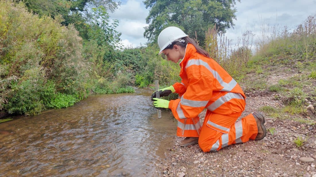 Environmental officer taking a turbidity reading beside a watercourse on a construction site