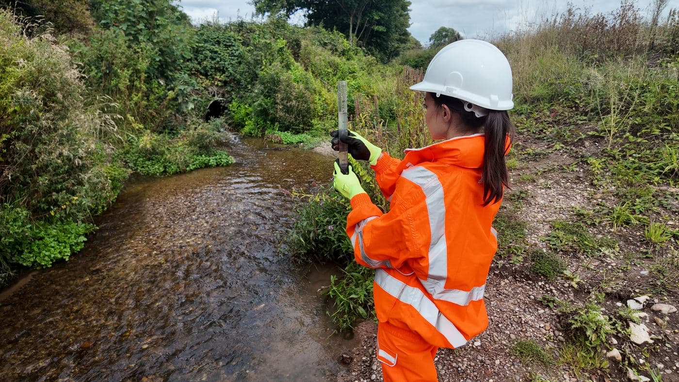 Environmental officer taking a turbidity reading beside a watercourse on a construction site